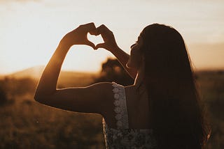 woman making the shape of a heart with hands