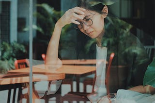 A woman looking frustrated, as seen through a coffee shop window
