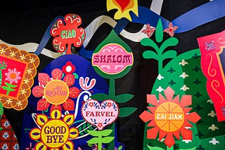 Photo of flowery sign from the exit in the Disneyland ride, It’s a Small World. The signs read send-offs in different languages.