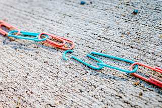 Turquoise and coral paperclip chain broken in the center.