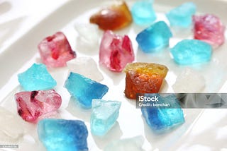 Several blue, red, white, and orange pieces of Kohakutou Japanese rock candy made from agar agar
