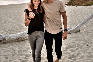 happy couple walking along beach holding hands