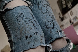 picture of a student’s legs in ripped jeans with Sharpie drawings on them.