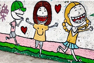 Street art of 3 happy children showing love with Chinese graffiti saying “Happy.” Photo taken by author in Hong Kong, 2015