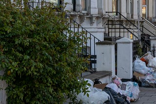 Bags full of garbage in front of rowhouses.