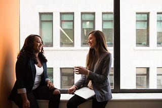 Two colleagues sit together having an actively engaged discussion about their work