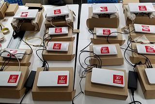 A set of WiFi routers and access points labeled with Mercy Corps stickers prepared for deployment