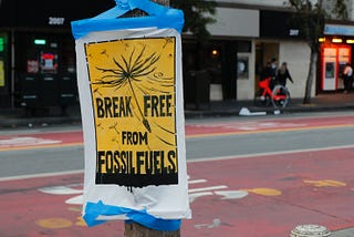 A poster attached to a street sign reads Break Free from Fossil Fuels.