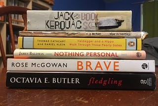 A stack of the six books read during March 2023, as listed in the article, set on top of a dining room table.