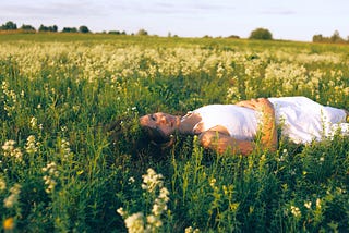 Woman in a white sundress laying in a field of flowers.