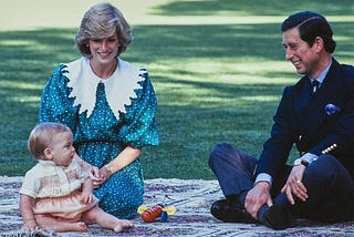 Princess Diana, Prince Charles and Prince William, are seated on a blanket on the lawn