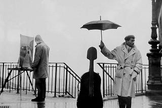 An artist at his eisel and a man holding an umbrella over his cello.