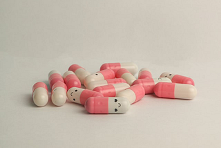 Pink and white pills with smily faces on them, Nyk, Medium