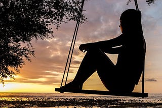 A woman sitting on a swing. By pexels