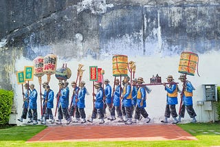 a mural on a building showing marching Chinese immigrants holding lanterns.