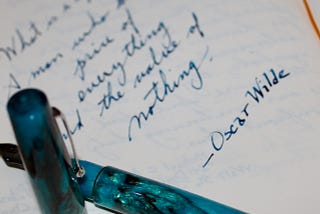 A fountain pen and notebook with a snippet from Oscar Wilde, “What is a cynic? A man who knows the price of everything and the value of nothing.”