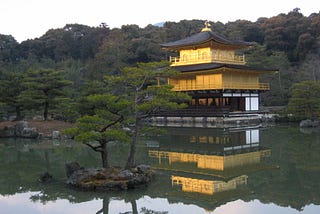 A japanese temple, reflected ina lake. Gold, and then green.