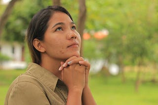 A woman praying and looking at the sky.