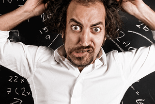 man pulling his hair and standing in front of a blackboard with math equations on there, resembling Albert Einstein, being used here to represent a CEO boss manager business owner who acts like a genius but is really an unstable leader.