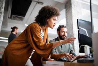 Women pointing to computer screen alongside male co-worker in an office enivornment