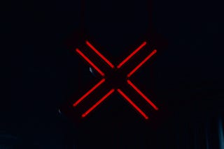 A red X sign glowing in the dark