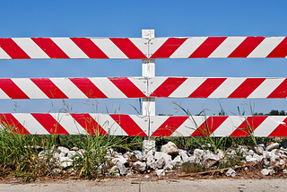 Photo of a red and white striped traffic barrier with blue sky in the background.