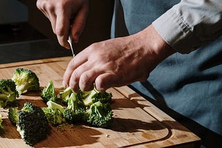 A close-up of a man chopping broccoli