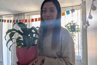 Photo of young woman holding a plant.