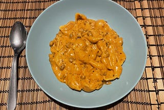 Bowl of shells in a creamy sauce with fake mince meat pieces in it.