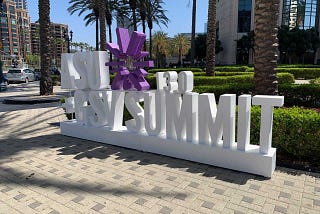 White 3-D lettering and purple sunburst logo spelling out ASU+GSV 13.0 Summit