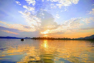 A golden sunset is reflected on the water of a lake.