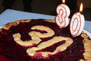 A pie that says 30 on it, and has candles that also show the number 30.