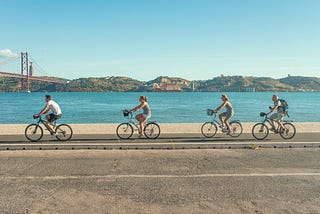 Four people riding a bike along the Tagus river.