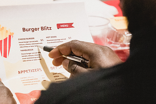 Judge Renel Domond, Co-Owner and COO of Juice Kings, carefully reviews the student menu at ‘The Wright Stuff’ food pitch competition, bringing expertise and discerning taste to the table (Photo by: Melissa Olguin)
