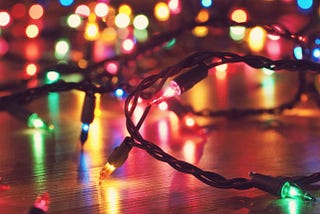 a strand of pink, green and yellow holiday lights is lying on a hardwood floor in a dark room