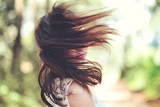 Girl, dark hair, white dress, out of doors, turns to camera, wind blows hair to obscure her face