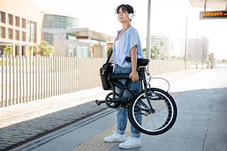 traveling beautiful woman standing holding a foldable bicycle