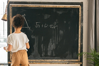 Unrecognizable girl solving mathematical problems near chalkboard · Free Stock Photo