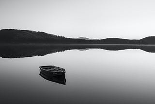 Row boat on calm water near mountain during daylight