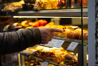 person choosing one pastry from a display case
