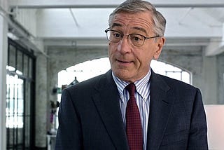 Robert DeNiro, a senior aged intern in the movie The Intern, wearing a suit and tie.