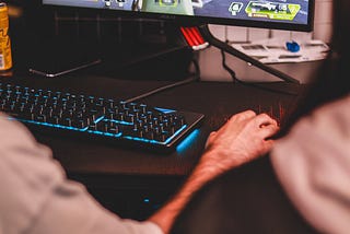A player using a gaming keyboard and mouse, while others watch him.