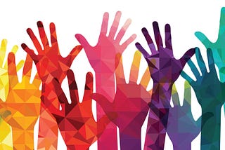 A mixture of vibrant rainbow coloured hands being held up against a white background.