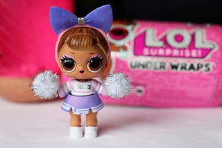 L.O.L. Doll in front of L.O.L. packaging