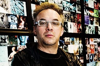 Digital media theorist and artist Lev Manovich wearing his signature square glasses in front of a collection of digital images — apparently unrelated to each other. His fascination with collections of data is the basis for his database narrative theory.