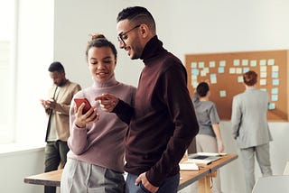 Two people looking at a phone smiling and discussing the user experience