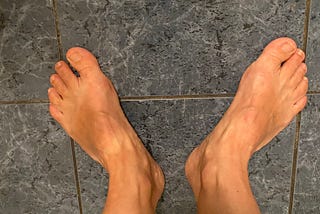 The author’s feet on a blue tile floor.
