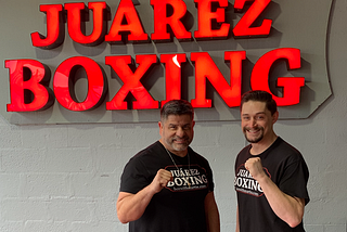 Martin Juarez and Dany Egli pose in front of Juarez Boxing sign