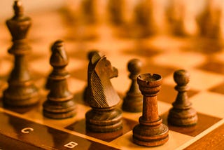 Closeup of a wooden chess board with wood chess pieces.