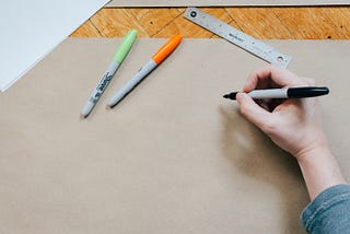 A blank piece of brown paper with a hand holding a marker